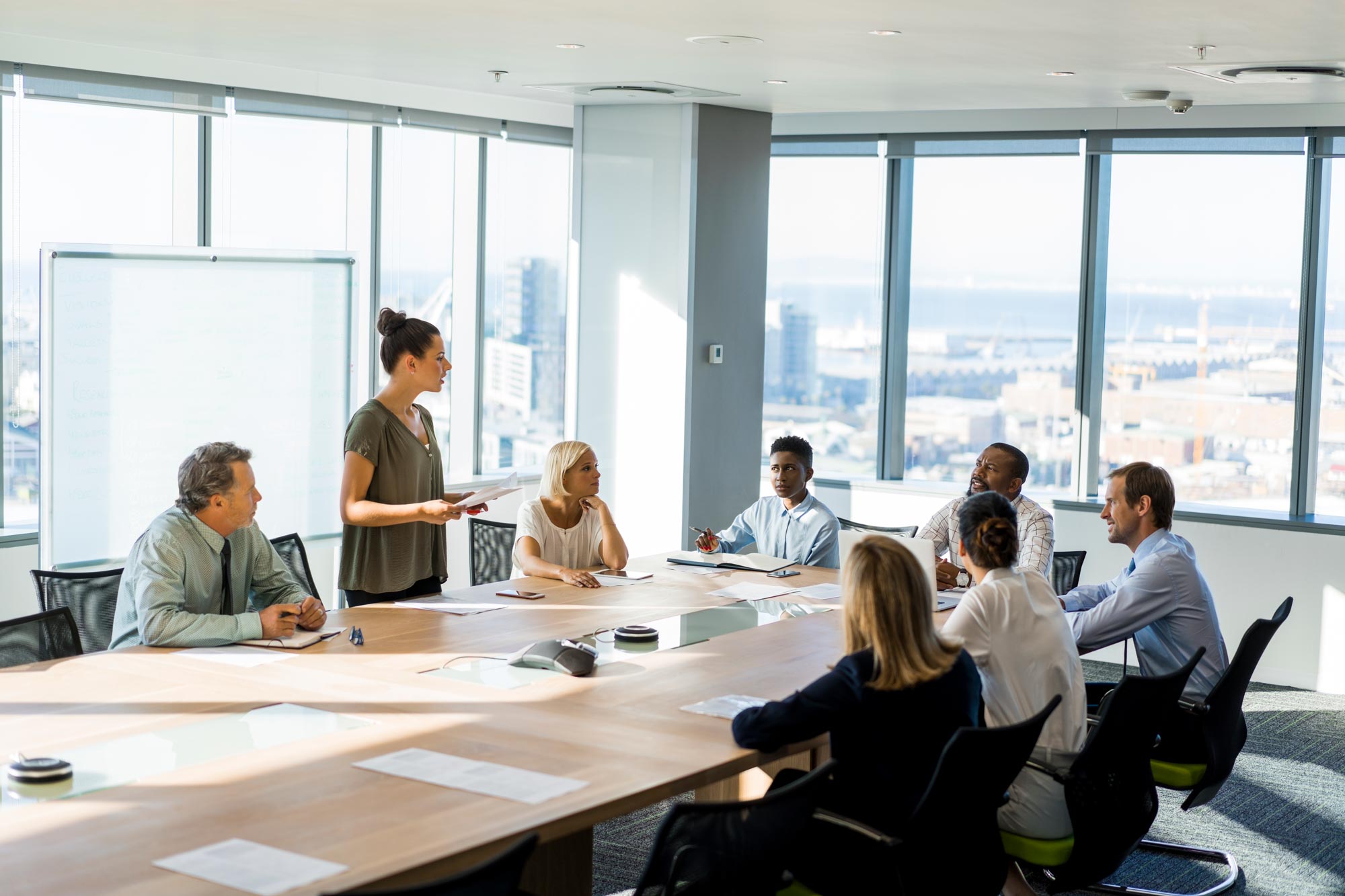 Presentation hålls framför flera personer runt ett bord i ett konferensrum