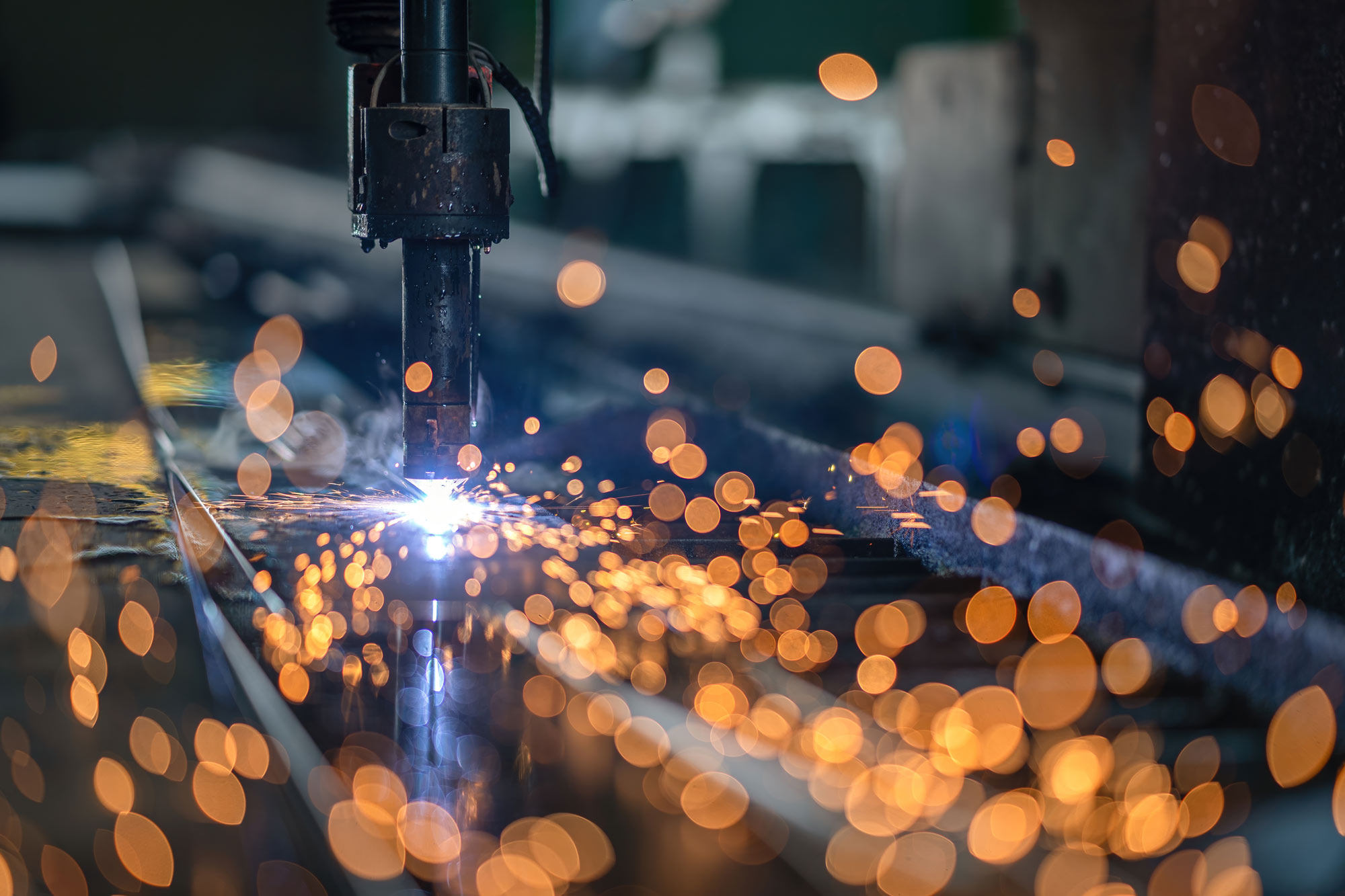 Industriell laserskärmaskin skär genom en metallplåt medan gnistor sprakar
