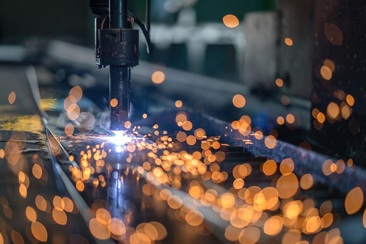 Industriell laserskärmaskin skär genom en metallplåt medan gnistor sprakar