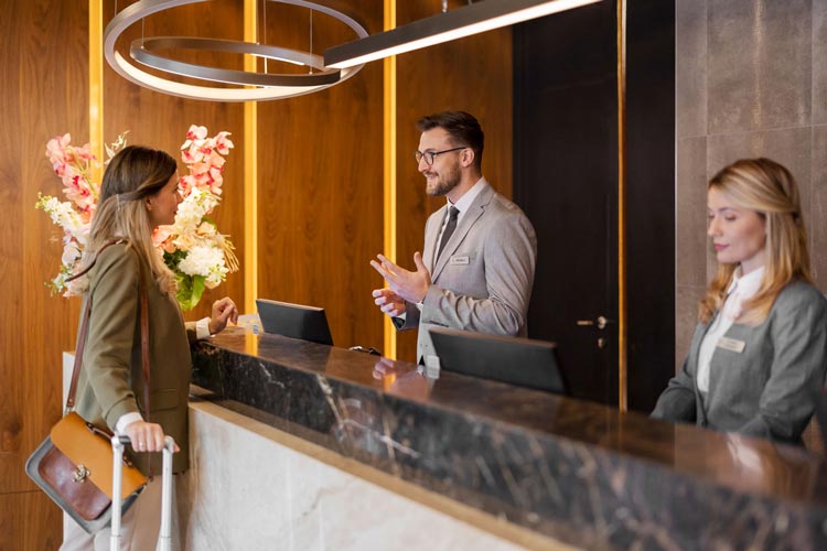 En besökare står vid receptionsdisken och samtalar med en receptionist i en modern och stilren reception